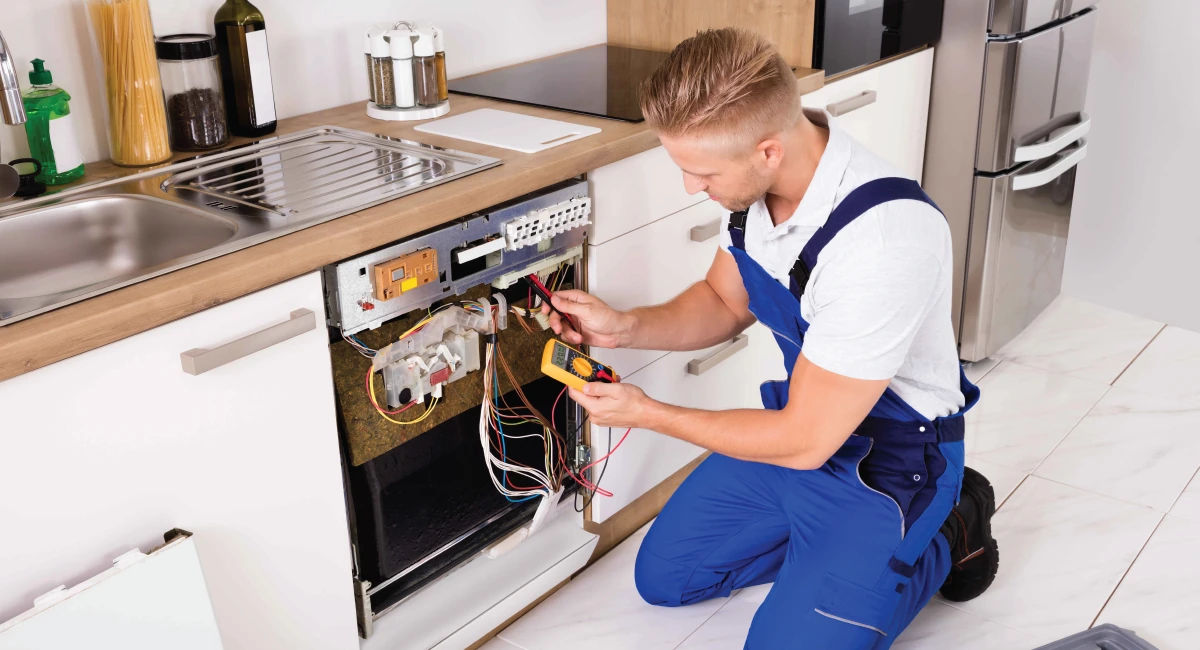 Technician testing exposed dishwasher controls in a home kitchen