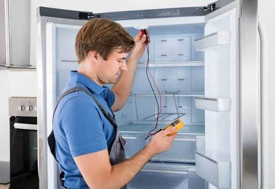 Technician using an electrical meter inside an open refrigerator