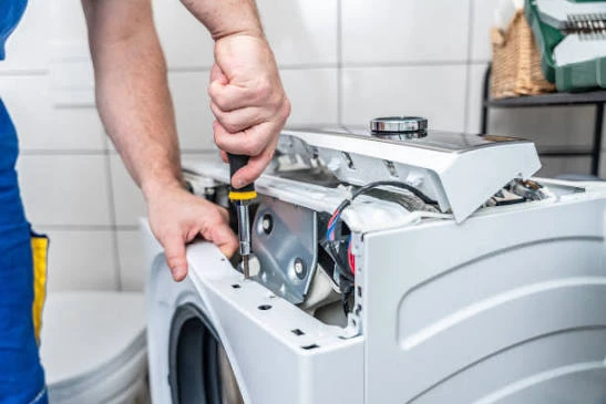 Close-up of a technician using a screwdriver on a washing machine component